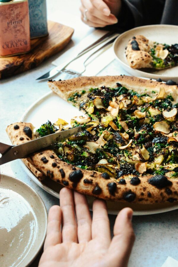 Delicious gourmet pizza with greens and mushrooms being served at a restaurant.
